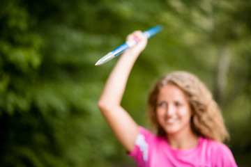 Young sportswoman holding up a javelin