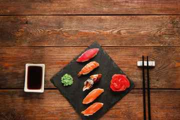 Tasty delicious set of five sushi nigiri served on black slate with ginger and wasabi, on wooden...