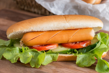 Hot dog with sausage, tomato, cucumber and lettuce.