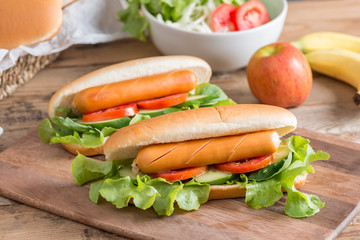 Hot dog with sausage, tomato, cucumber and lettuce.