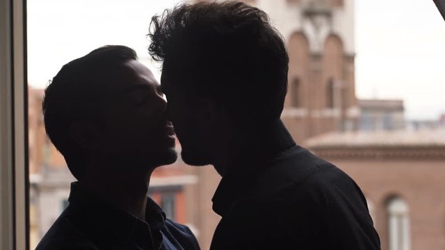 gay men Silhouette kissing sweetly near the window