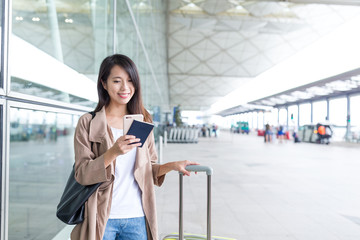 Woman using cellphone with her luggage in airport