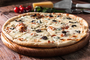 Appetizing baked homemade pizza on wooden rustic table served with ingredients. Traditional italian food, restaurant menu photo.