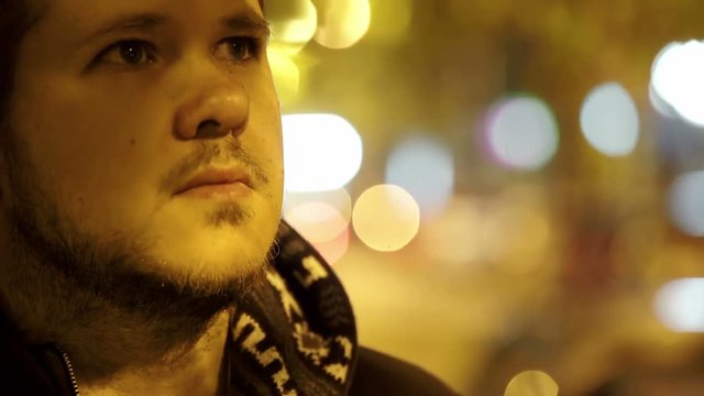 Sad and thoughtful man raising his eyes, city night