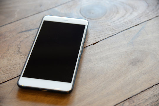 White Smart Phone In Black Case On The Wood Table Prepared For Management Teams To Contact With Customer In Business