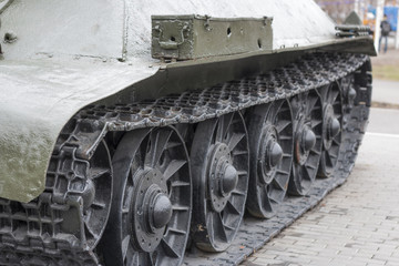view of the front part of the green caterpillar of the tank standing on the ground with the wheels close-up - 145535877