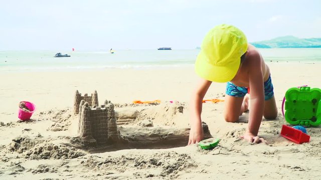 blonder bub spielt mit sand auf einem strand in thailand