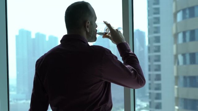 Young businessman drinking red wine and looking through tke window, HD
