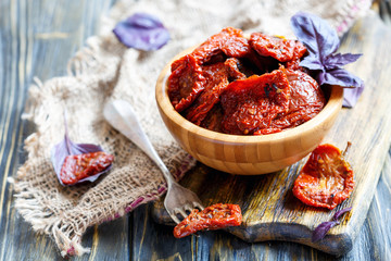 Sun-dried tomatoes in wooden bowl and a fork. - obrazy, fototapety, plakaty