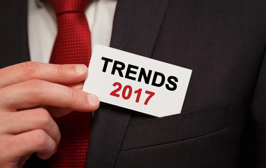 Businessman putting a card with text Trends 2017 in the pocket