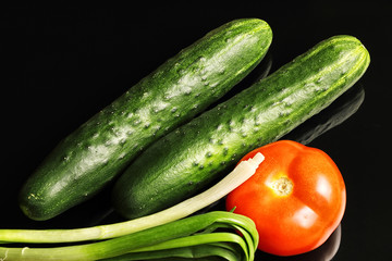 Pimpled cucumbers and greenhouse tomatoes with herbs onion isolated on a black background