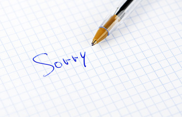 The word sorry written on sheet of paper with pen.