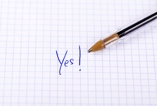 The word yes written on sheet of paper with pen.