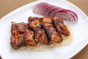 Grilled pork ribs served with pita and red onion