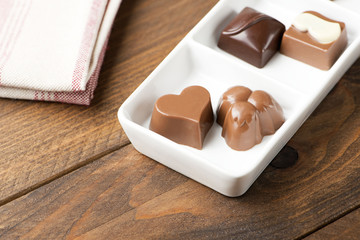 Chocolates with different shapes on white plate. Food.