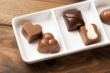 Delicious chocolates with different shapes on white plate. Food.