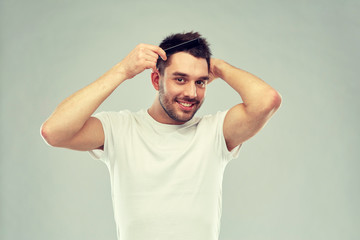 Fototapeta na wymiar happy man brushing hair with comb over gray