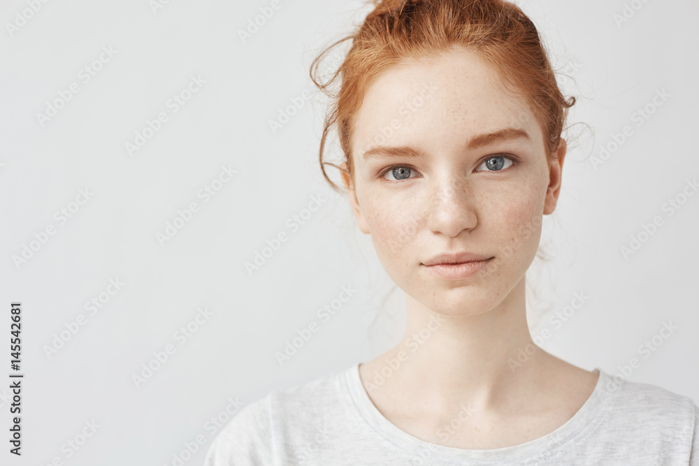 Sticker Close up portrait of young beautiful redhead girl in white shirt smiling looking at camera. Copy space. Isolated on white background.