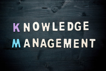 wooden word knowledge management on background business concept