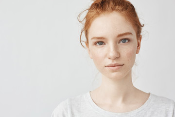 Fototapeta premium Close up portrait of young beautiful redhead girl in white shirt smiling looking at camera. Copy space. Isolated on white background.