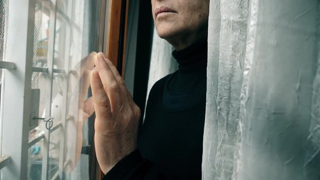 Close up on hand of mature woman leaning against window
