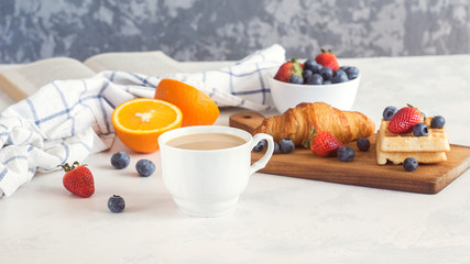 Obraz na płótnie Canvas Cup of coffee, juice, fresh berries and croissants on white background. Morning breakfast