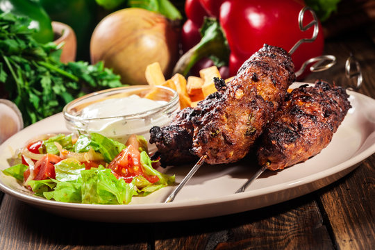 Grilled shish kebab served with fried chips and salad