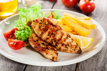 Grilled chicken breasts served with fries and fresh salad
