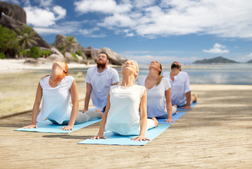 group of people making yoga exercises over beach