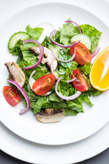Salad of vegetables and champignons on white tableware top view.