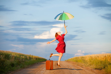 photo of beautiful young woman with suitcase and umbrella on the road near field background © Masson