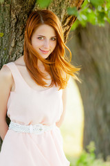 portrait of beautiful young woman near tree on the wonderful park background