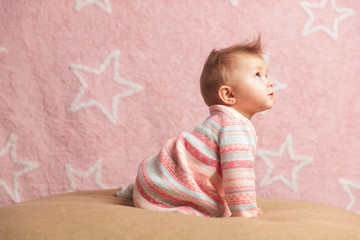side view of a crawling baby girl looking up