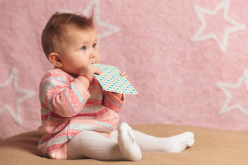 side view of a baby girl biting on a card