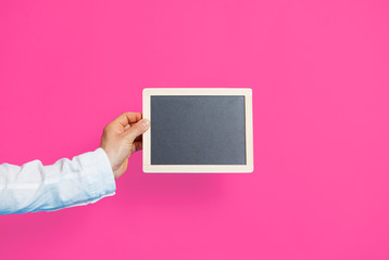 photo of male hand holding empty board on the wonderful studio pink background
