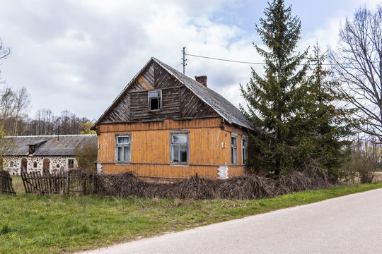 An abandoned wooden house with walls painted yellow-orange paint. Spring in the Region Podlasie, Poland.