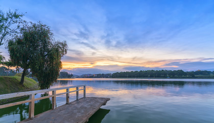 Fototapeta na wymiar Da Lat, Vietnam - March 27th, 2017: Sunset on the shores of Xuan Huong Lake with dramatic sky makes the scenery more romantic, attracting tourists to visit in Dalat, Vietnam.