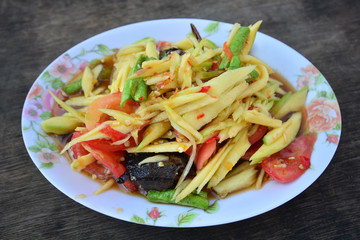 Green papaya salad Thai cuisine spicy delicious on wooden plate , SomTam