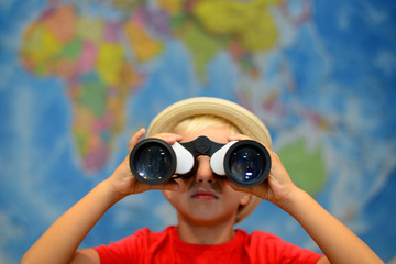 Kid with binoculars is looking around. Adventure and travel concept. Creative background. Boy is playing in captain.