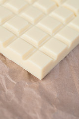 Close-up of white chocolate bar over paper