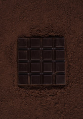 Top view of a dark chocolate bar over chocolate powder