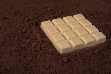 White chocolate bar over milk chocolate powder