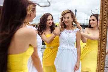 Beautiful Bride and two bridesmaids in yellow similar dresses together on a summer terrace a sea restaurant