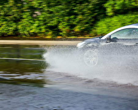 Car Moving Through A Puddle On A Flooded Street With The Risk Of Aquaplaning