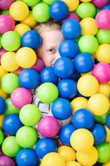 Fototapeta na wymiar Child completely hid in colorful balls