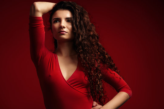 beauty model with long curly hair on red background