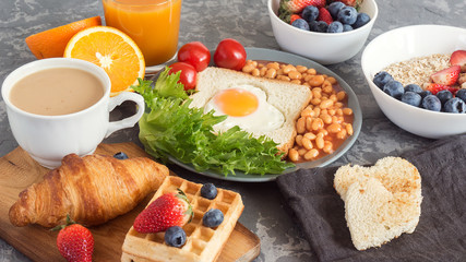 Full English Breakfast with fried eggs, beans, toasts, salad, tomatoes on gray background