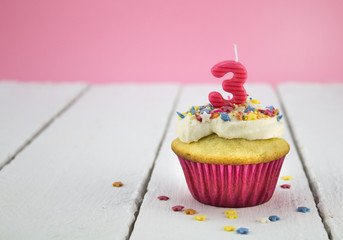 Happy birthday cup cake with star sprinkles and number 3 pink candle on white tabel with pink background - Birthday celebration background for a little girl - photo