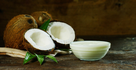 Fresh nourishing coconut milk moisturizing cream for hands, face and skin, on a dark wooden background, concept: spa, skincare, beauty, healthy lifestyle, bio products, ecologic products, massage.