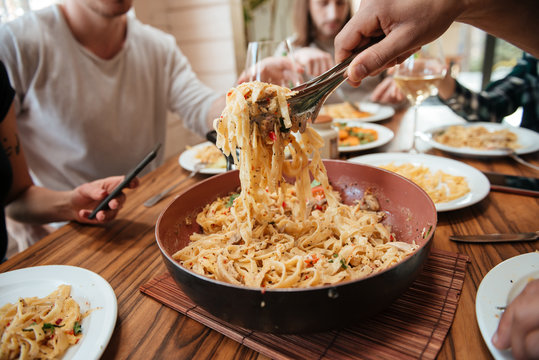 Closeup of people eating pasta on the kitchen at home